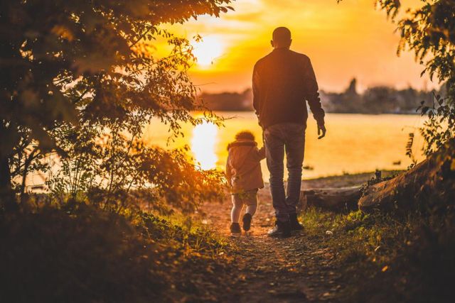Grandfather and grandchild walking at sunset